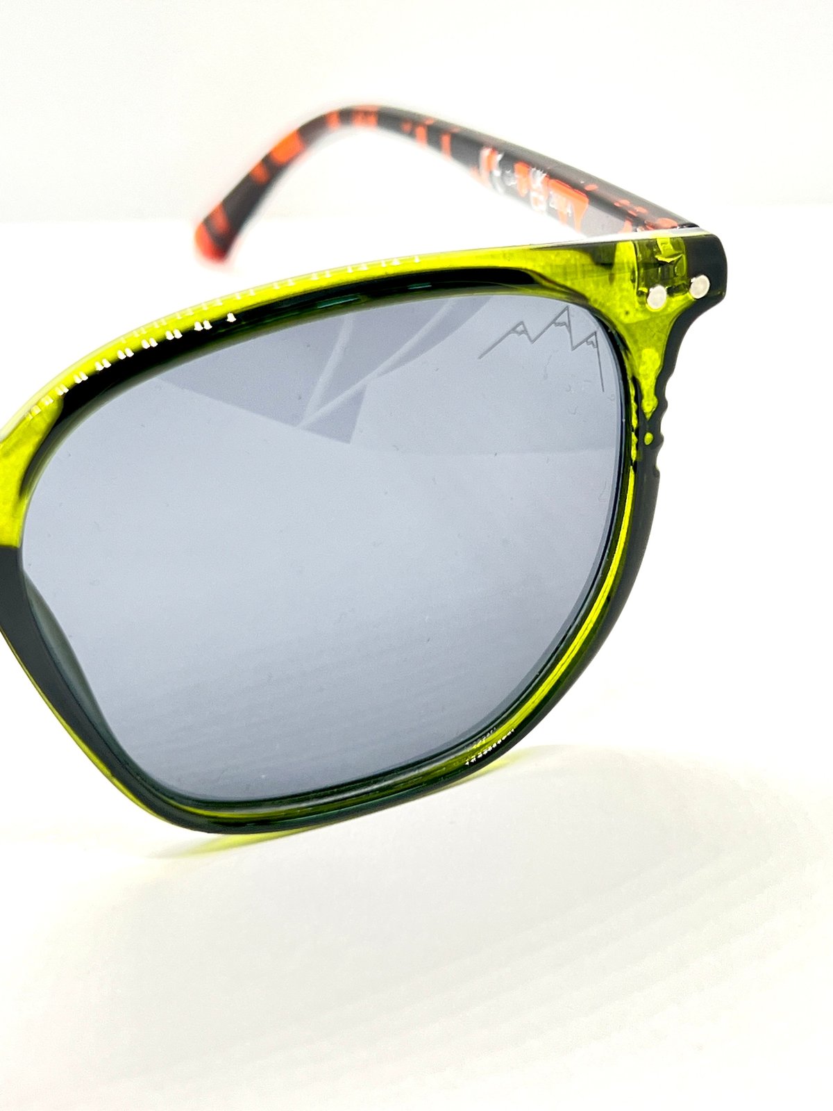 Neon yellow sunglasses with mirrored blue lenses and tortoiseshell arms on white background