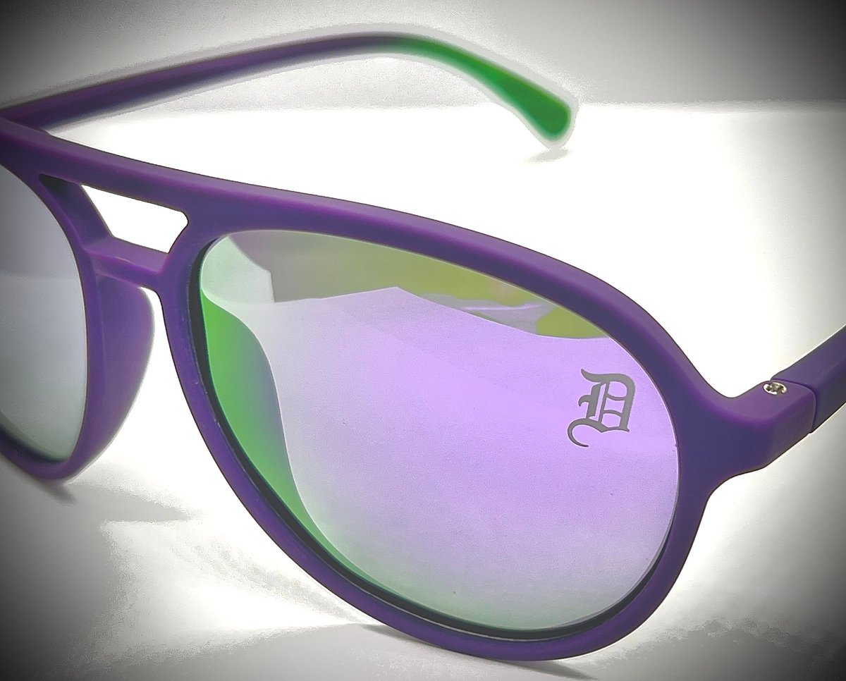 Purple sunglasses with iridescent pink and green mirrored lenses and green temple tips on white background