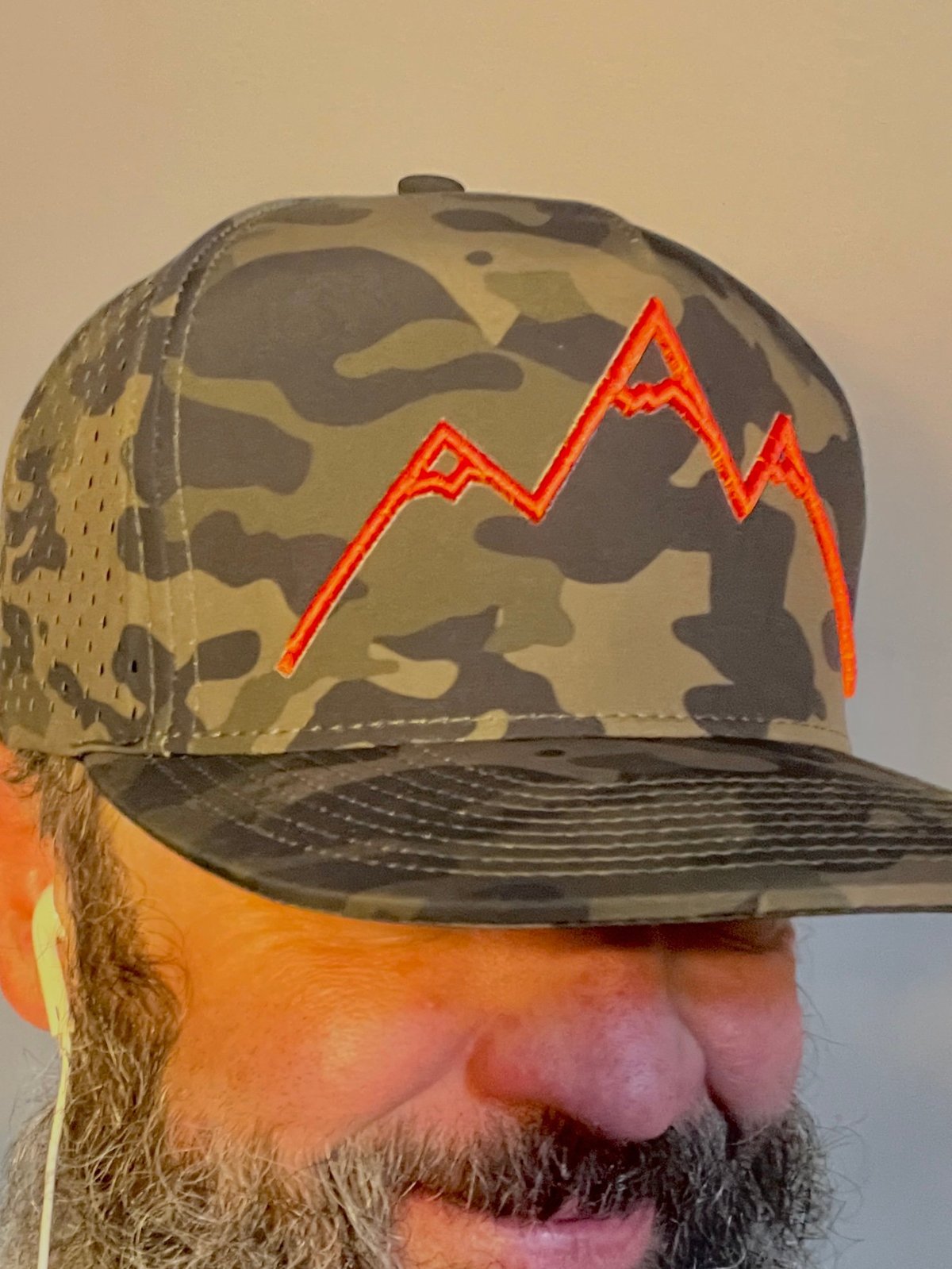 Person wearing camouflage trucker cap with neon red stock market chart graphic on front