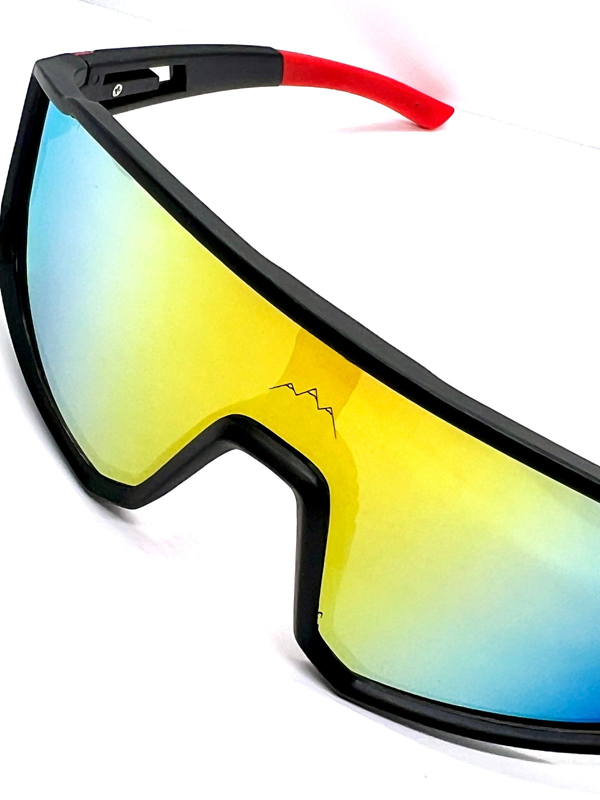 Black ski goggles with mirrored yellow and blue gradient lens and red temple arm against white background