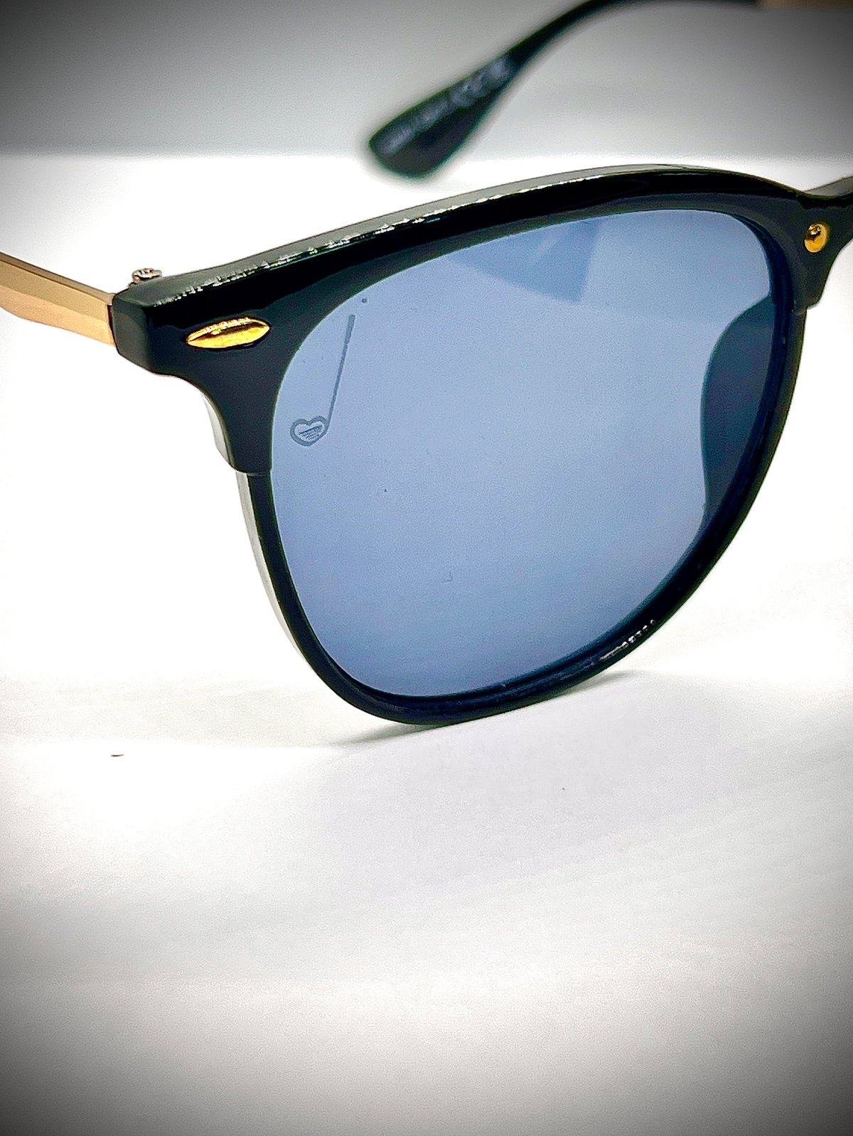Black sunglasses with blue-tinted lenses and gold accents on a white background